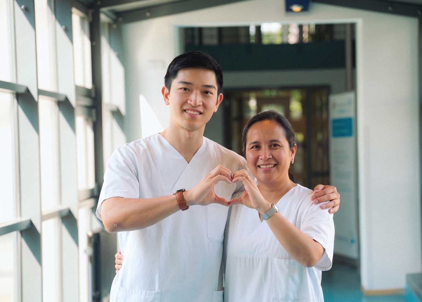 Paola und Michael, zwei internationale Pflegefachkräfte, lächeln gemeinsam.